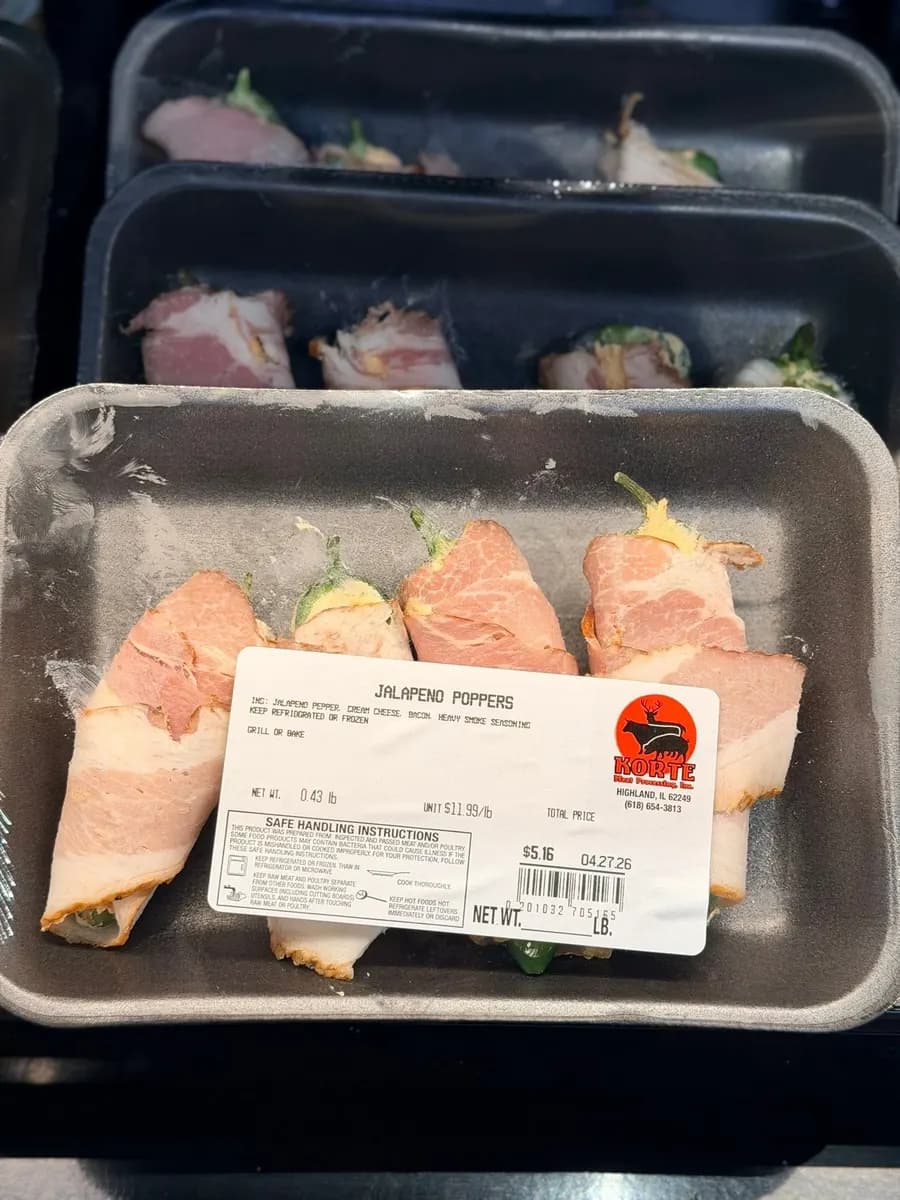 A tray of bacon-wrapped jalapeño poppers with a scale label showing weight, price and safe handling instructions