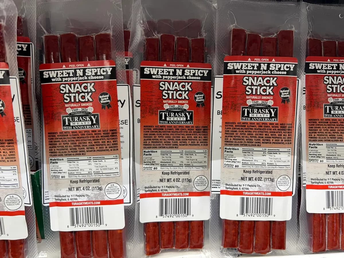 Packs of sweet and spicy snack sticks hanging in a retail display, each with a full-color printed label